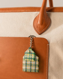 Plaid keychain attached to a brown leather bag 