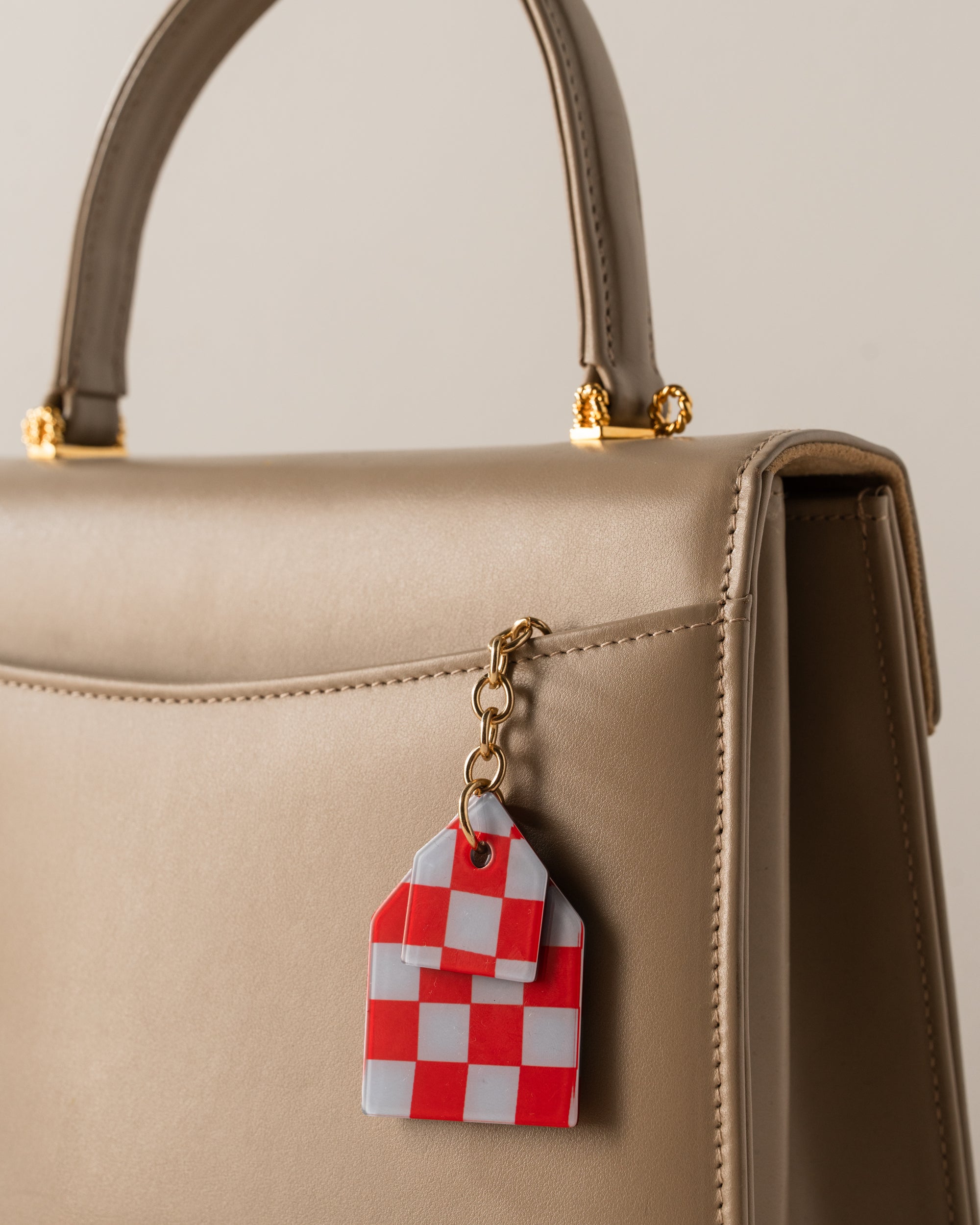 Beige handbag with a red and white checkered keychain attached