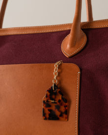 Tortoiseshell luggage tag attached to a brown and burgundy bag